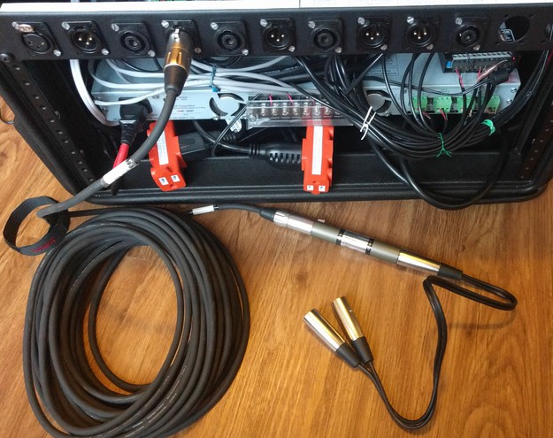 The rear of the rack case with a long XLR cable, a signal attenuator, and an XLR splitter