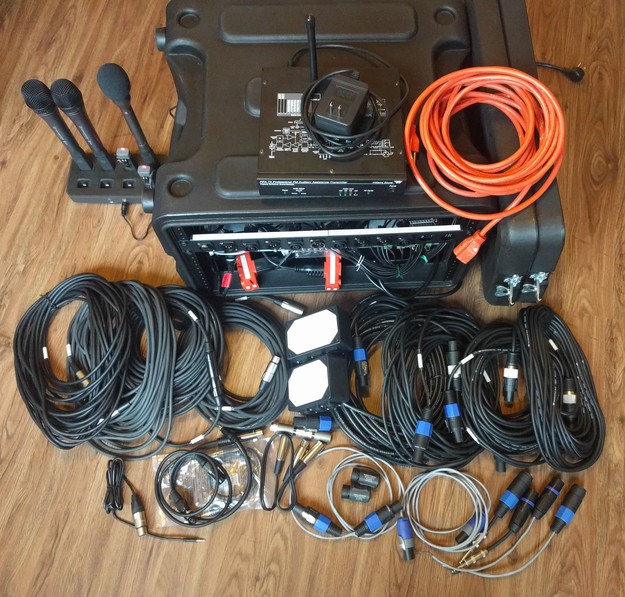A rear view of the systemn showing all cables and adapters, microphone charger, and assistive listening transmitter, as well as an extension cord and front and rear case covers